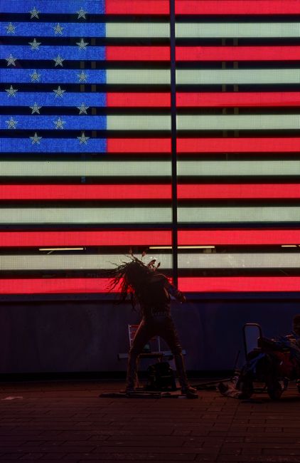 A dynamic silhouette of a street performer in front of the American flag in Times Square, New York City.