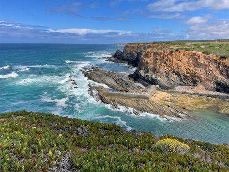 Breathtaking view of rocky cliffs and the Atlantic Ocean in Alentejo, Portugal, under a blue sky.