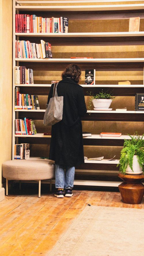 Free A person browsing books in a warm, cozy library setting in Istanbul, Türkiye. Stock Photo