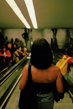 A woman descends an escalator in a bustling Porto metro station, captured with a cinematic feel.