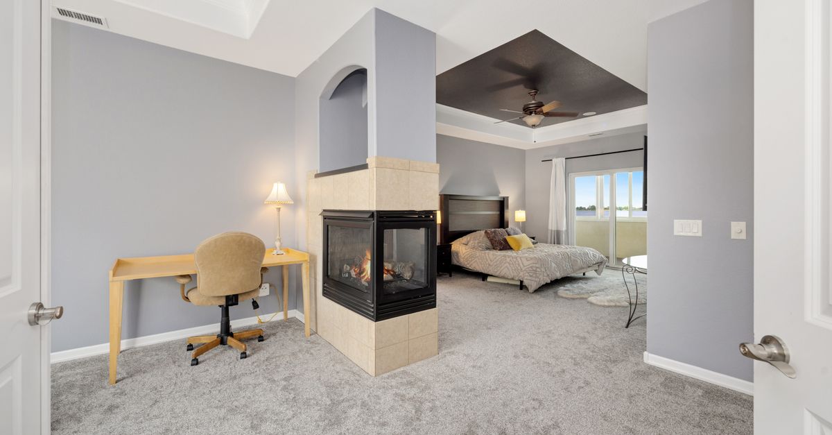 Elegant modern bedroom featuring a cozy fireplace and minimalist design with desk setup.