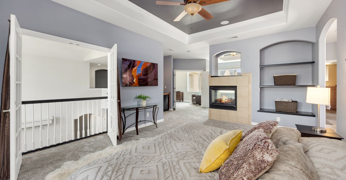 Spacious bedroom featuring a fireplace, stylish decor, and modern furnishings.