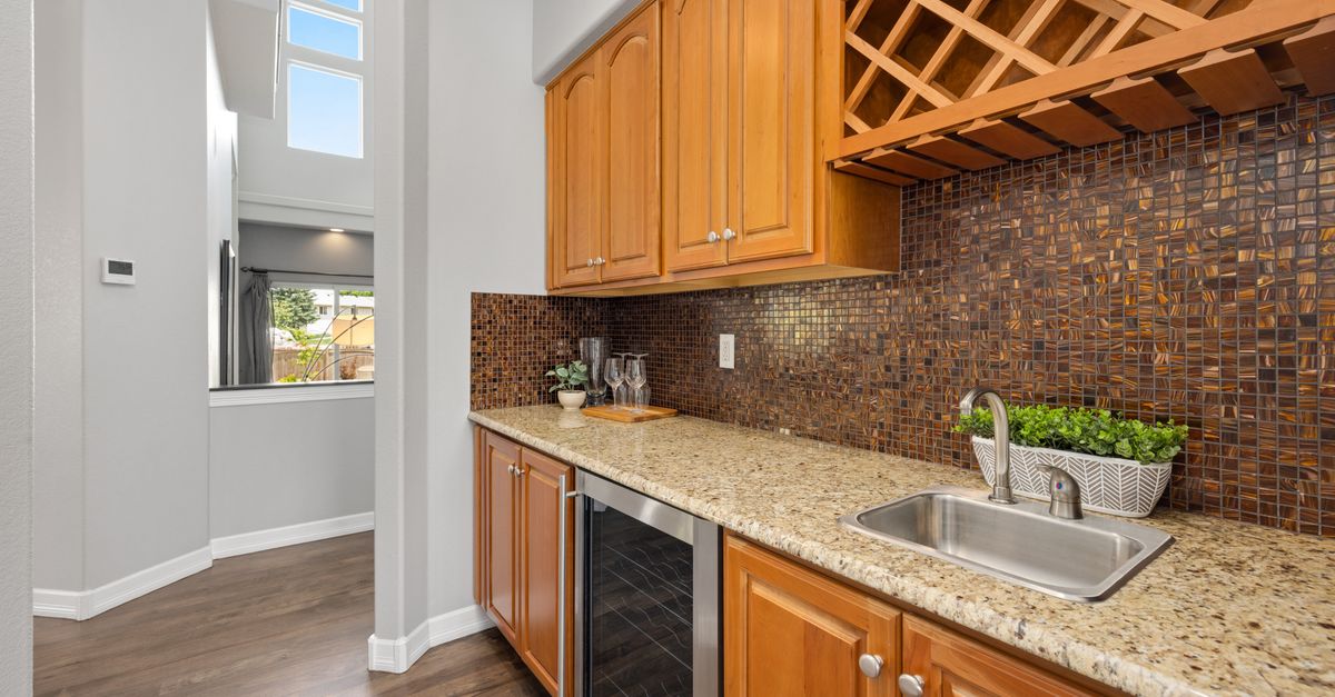 Elegant kitchen interior featuring granite countertops, wooden cabinets, and a mosaic backsplash.