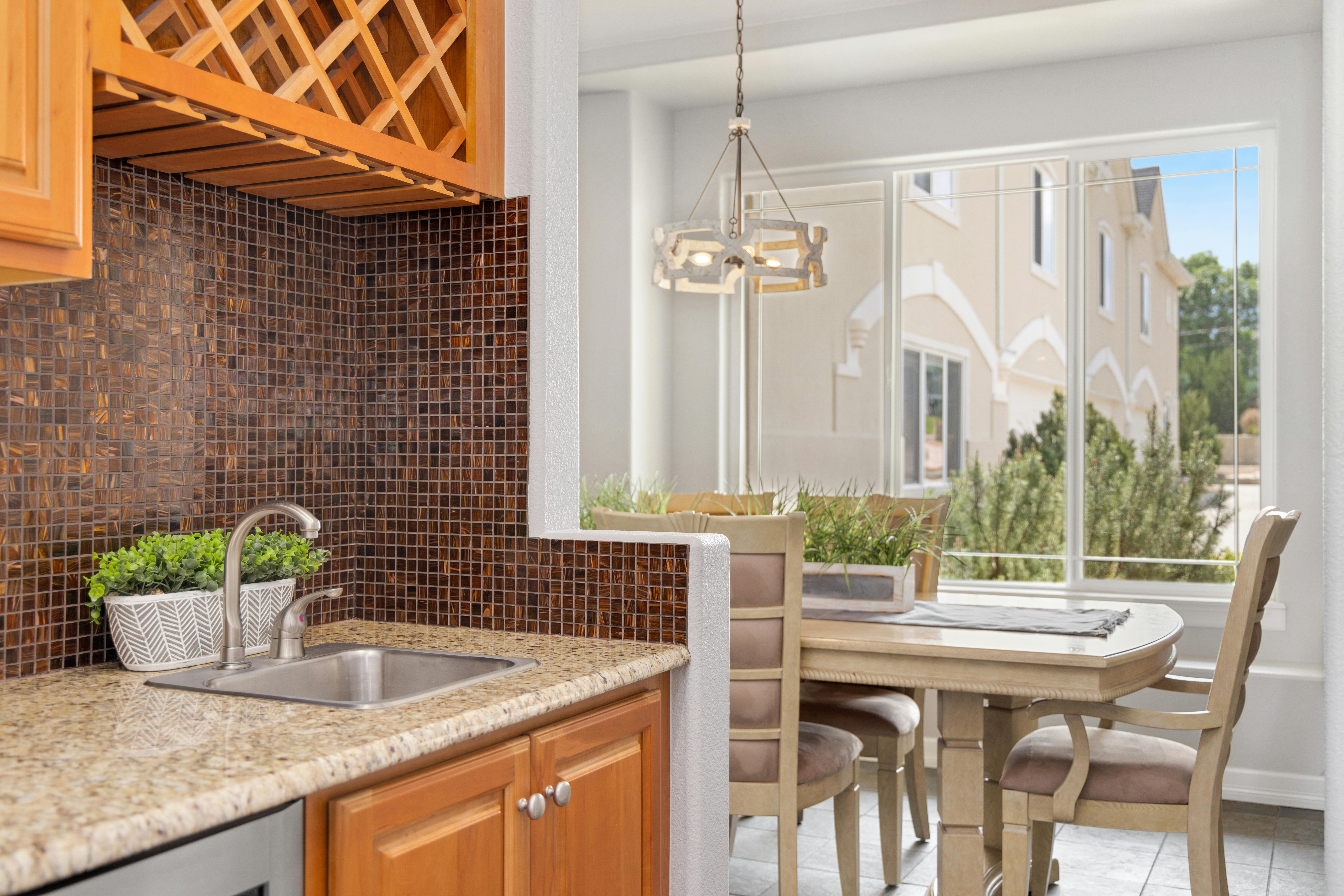 Contemporary kitchen and dining area with wooden cabinets and mosaic tile backsplash.