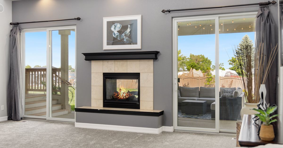 Elegant living room interior with a fireplace, gray walls, and sliding doors leading to a patio.