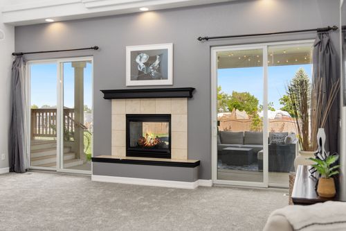 Free Elegant living room interior with a fireplace, gray walls, and sliding doors leading to a patio. Stock Photo