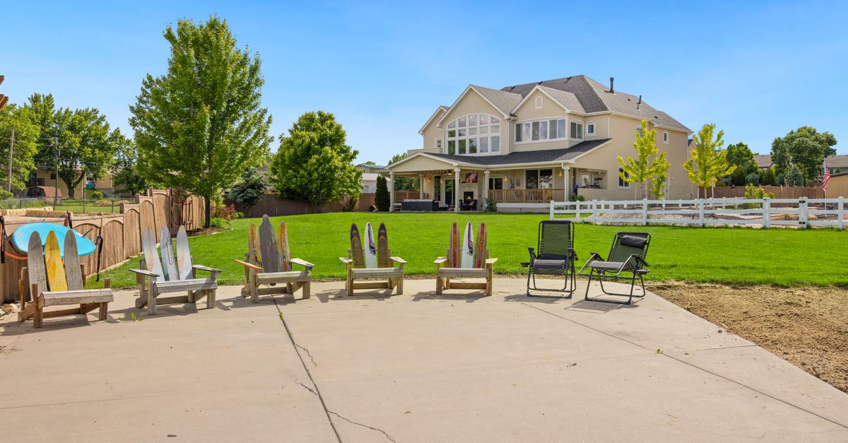 Spacious suburban home with deck chairs and lush garden under a clear summer sky.