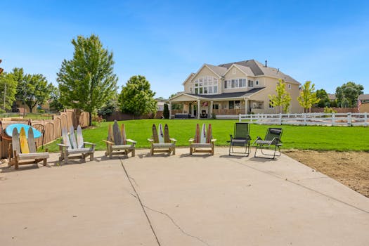 Spacious suburban home with deck chairs and lush garden under a clear summer sky.