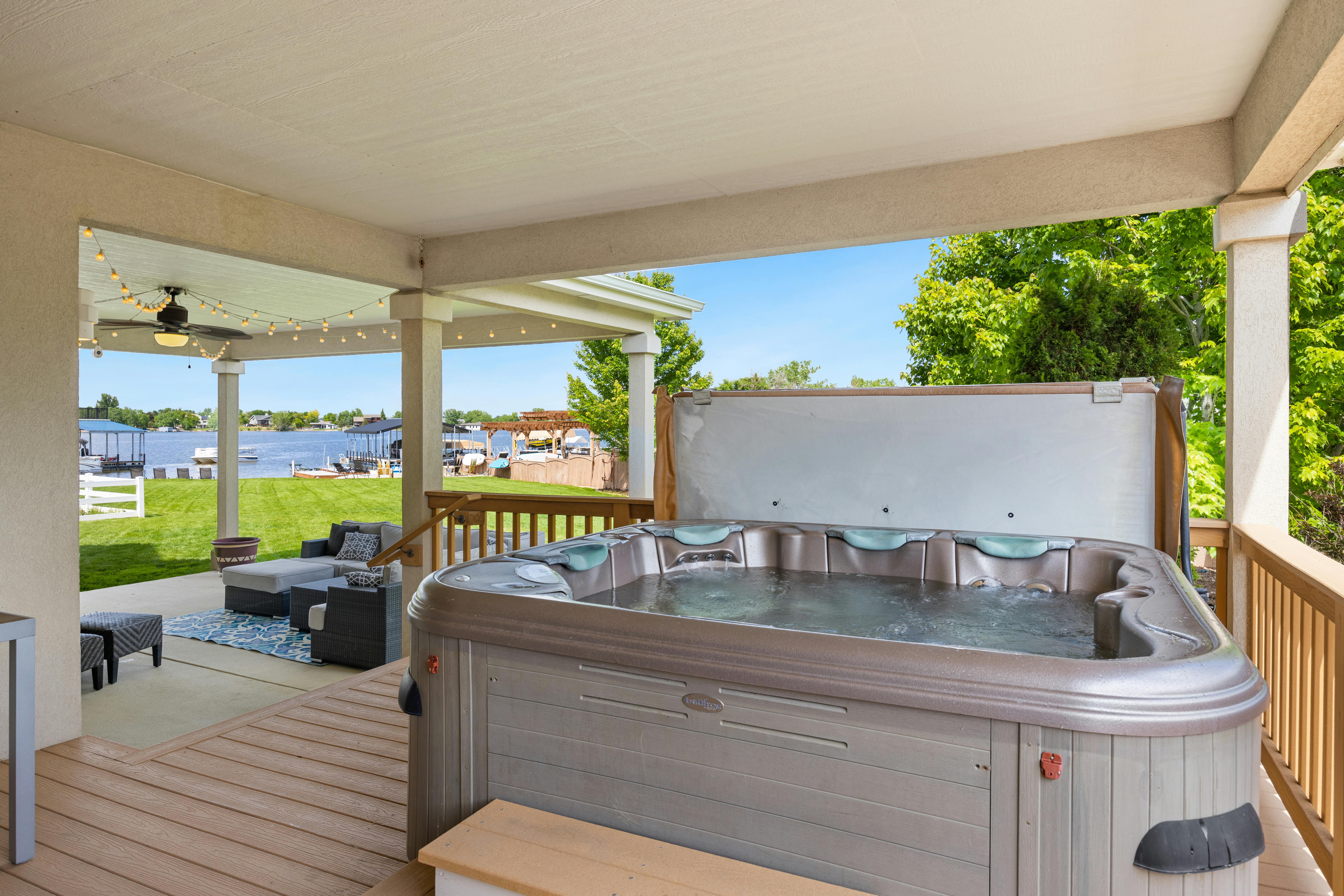 Explore a serene outdoor patio featuring a luxurious hot tub overlooking a tranquil lake.