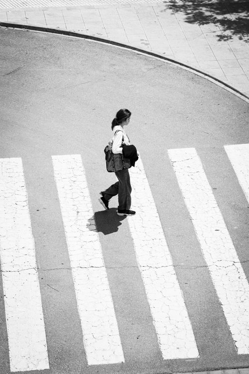 Free Aerial view of a woman crossing a street on a zebra crossing in Valencia, Spain. Urban life and pedestrian concept. Stock Photo