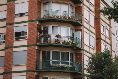 Free A beautiful urban building in Valencia with flower-adorned balconies and greenery, perfect for architectural themes. Stock Photo