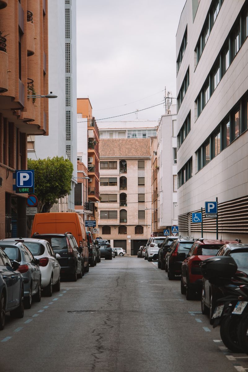 Stradă îngustă cu mașini parcate pe ambele părți într-un oraș european
