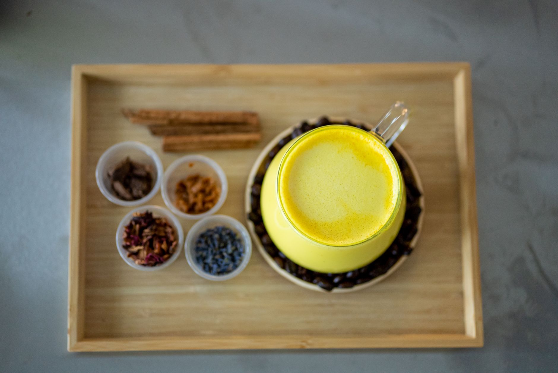 Turmeric root and powder next to a glass of warm golden milk on a kitchen counter in India