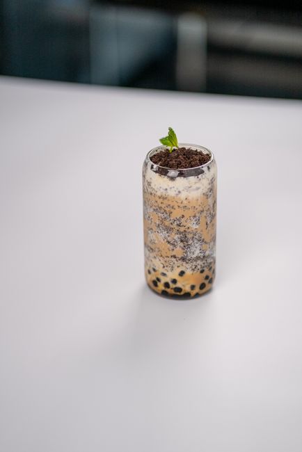A glass of brown sugar boba milk tea with dark caramelized syrup striping the inside of the glass and chewy tapioca pearls settled at the bottom.