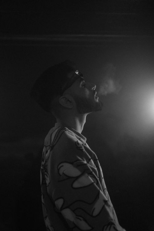 Free A striking black and white profile portrait of a man exhaling smoke indoors. Stock Photo