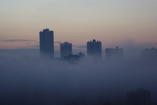 Free Misty cityscape with skyscrapers emerging from fog during twilight, evoking an urban mystery. Stock Photo