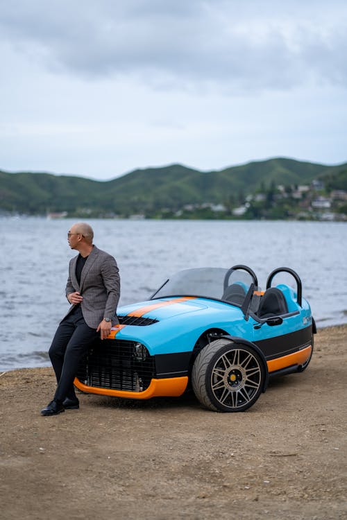 Man in Jacket Sitting on Hood of Vanderhall Carmel Roadster