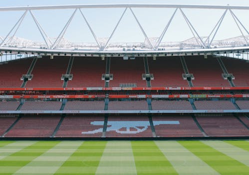 View of Arsenal's iconic Emirates Stadium with empty stands and lush football pitch.