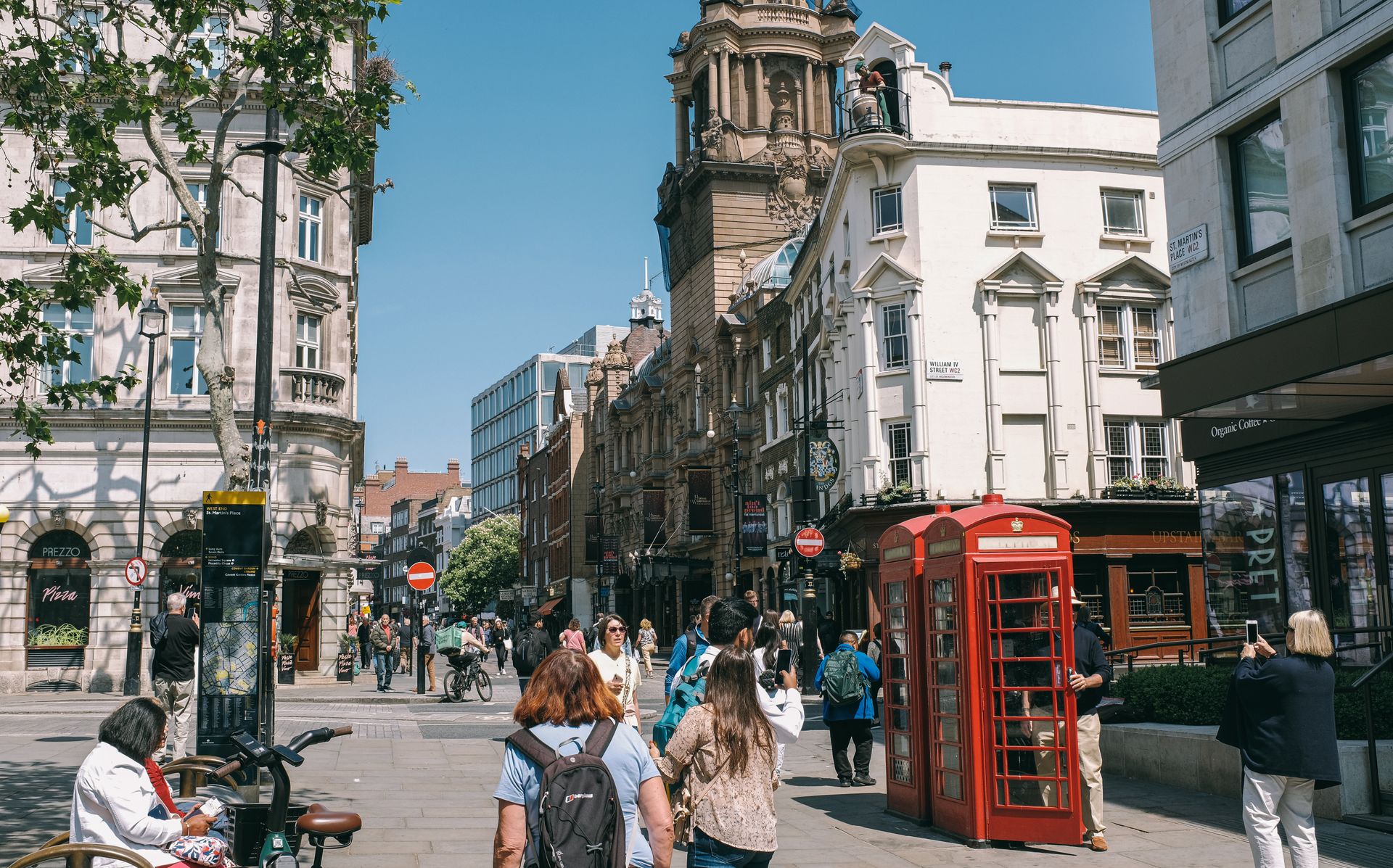 Vibrant city street scene in London featuring a historic red telephone booth and bustling pedestrians.