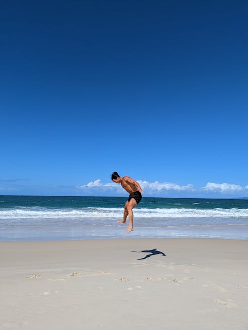 Man in Shorts Jumping on Beach