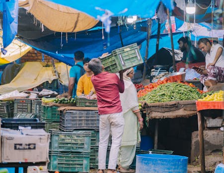 A vibrant market scene showing vendors and shoppers, surrounded by fresh produce and colorful stalls.