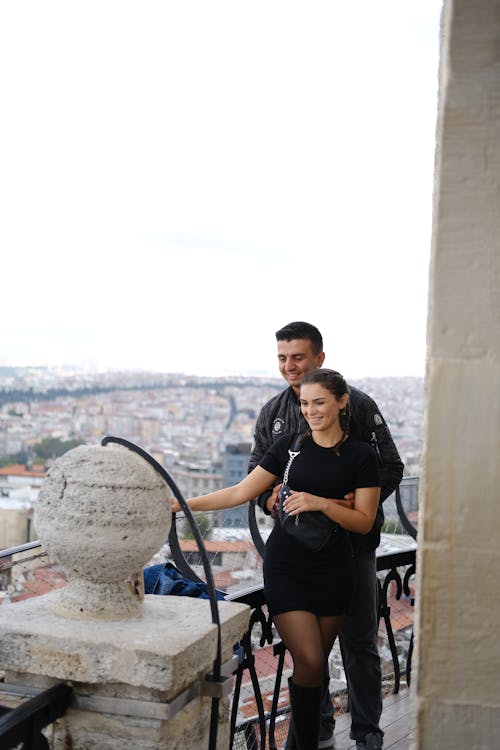 Man and Woman in Black Dress Posing Together on Balcony