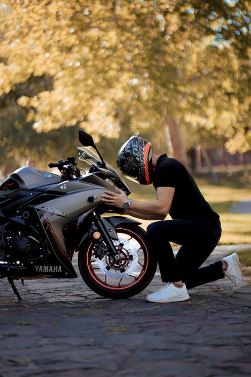Free A motorcyclist kneeling by a Yamaha bike outdoors during the day. Stock Photo