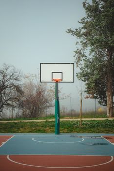 Serene outdoor basketball court in a park setting during springtime in L'Aquila, Italy.