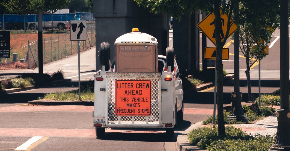 A city litter crew vehicle on an urban street, indicating frequent stops.