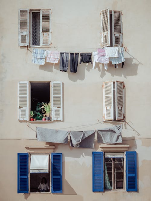 Townhouse with Colorful Wooden Shutters and Laundry Hanging from the Window 