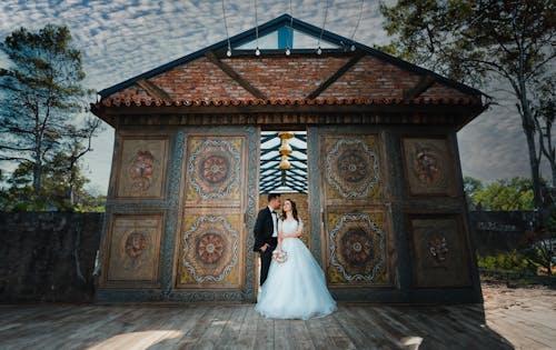 Newlyweds Standing by Ornamented Building Wall
