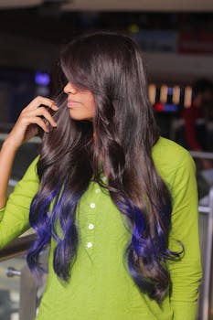Portrait of a woman with long brunette hair and blue tips, wearing a green top indoors.