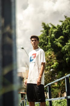 一名年轻人自信地站在户外桥上，穿着休闲服装