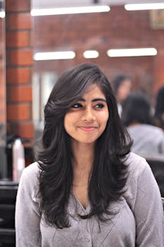 Portrait of a smiling woman with long dark hair in a modern indoor setting.