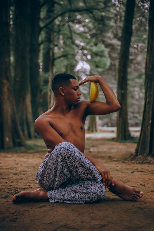 Depth Photography of Man Sitting Holding Yellow Citrus Fruit