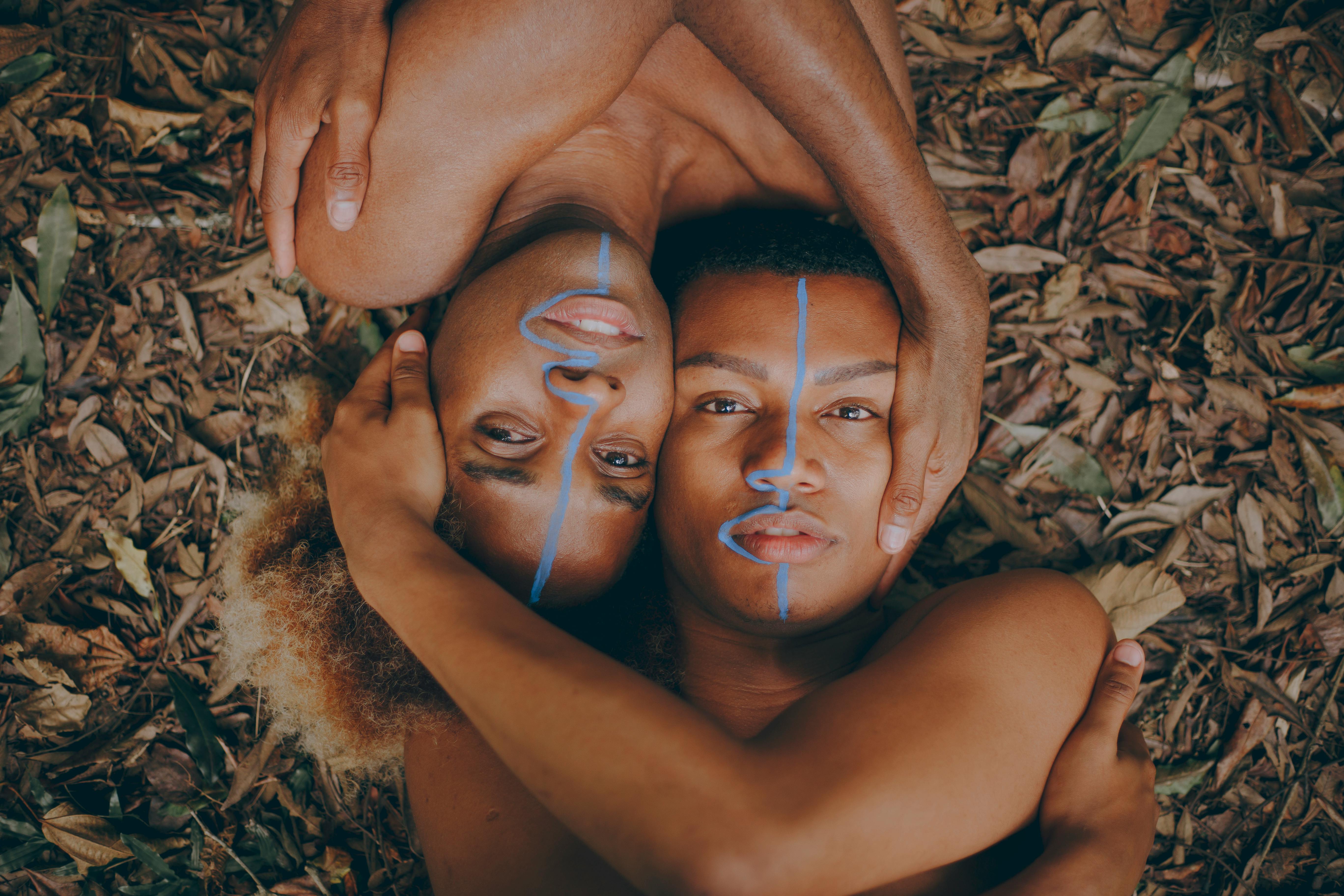 two people laying on dry leaves