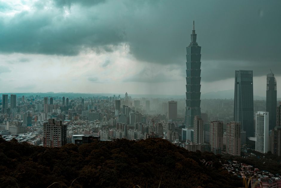 Explore the dynamic skyline of Taipei with the famed Taipei 101 building amidst a cloudy backdrop.