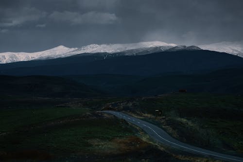 Highway and Snowcapped Mountains under a Storm Cloud 
