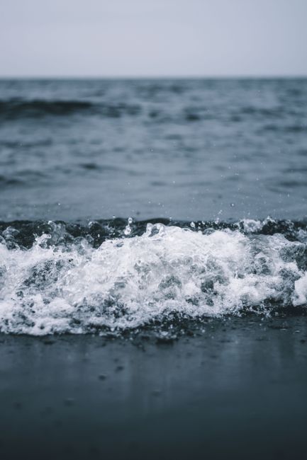Capture the motion and energy of ocean waves breaking on a serene shoreline, creating a dynamic aquatic scene.
