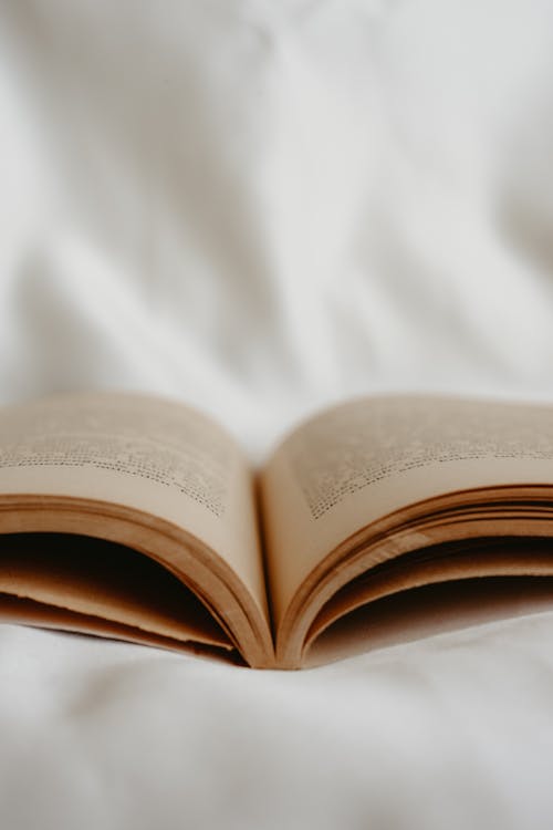 Close-up of an Open Book Lying on White Fabric 