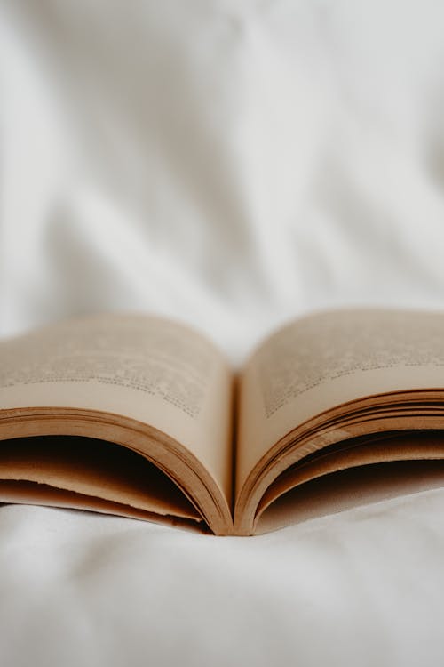 Close-up of an Open Book Lying on White Fabric 