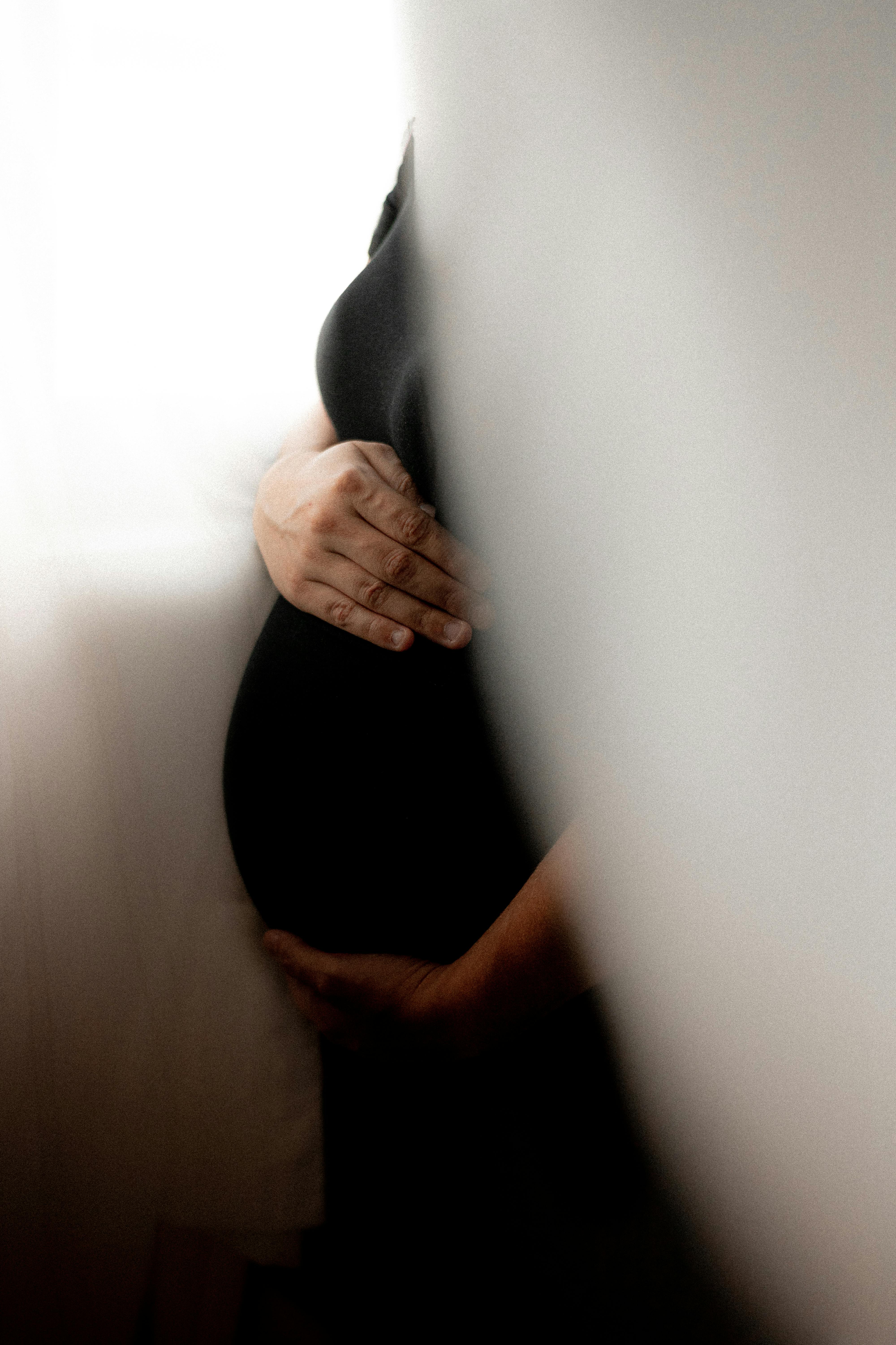 bared pregnant girl in transparent clothes embraces the stomach, isolated  on black background Stock Photo - Alamy
