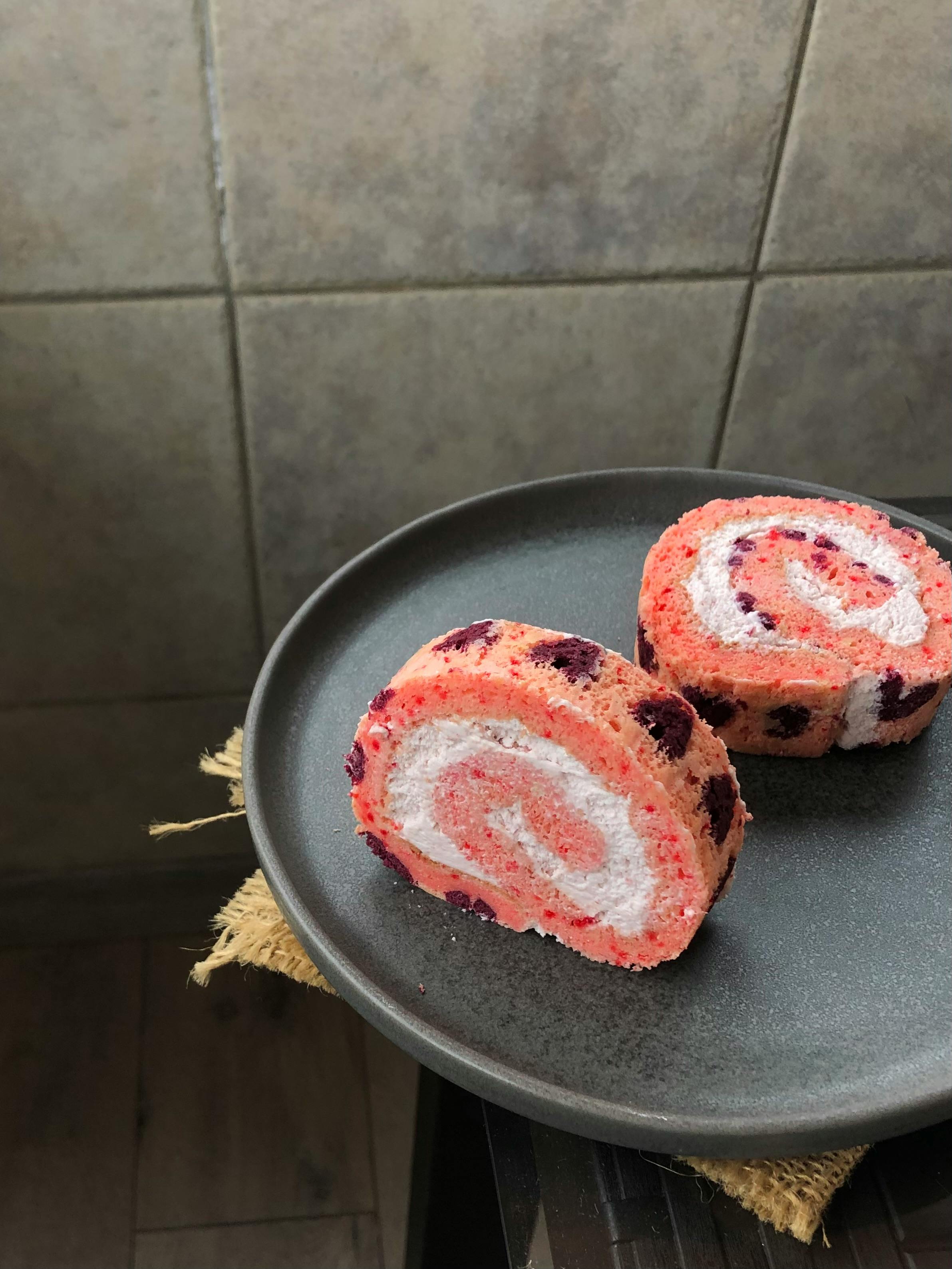 Close-up of a colorful roll cake on a plate, showcasing detailed textures and vibrant colors.
