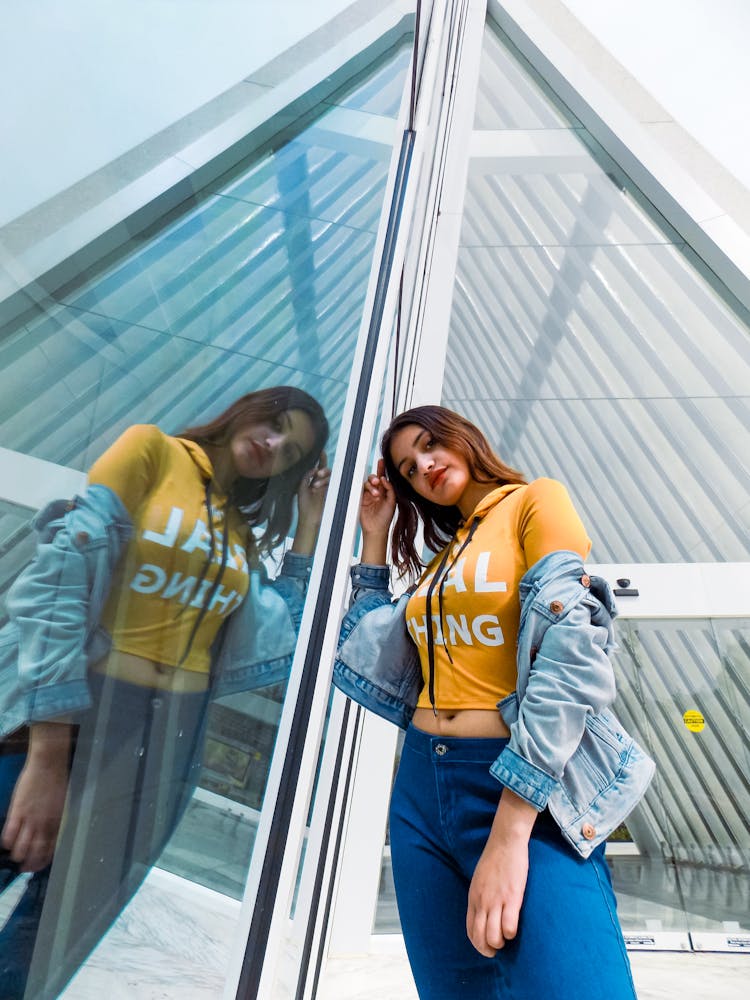 Young Woman Standing Next To A Window Of A Modern Building In City 