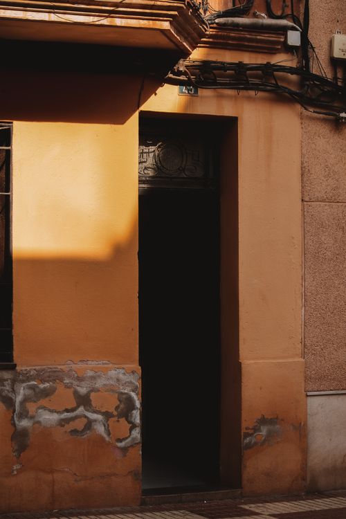 Free A rustic urban doorway bathed in warm sunset light, showcasing textured plaster walls and shadow play. Stock Photo