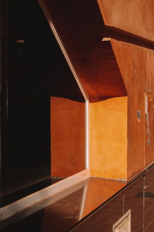 Free Striking geometric patterns and shadows on a modern orange building facade. Stock Photo