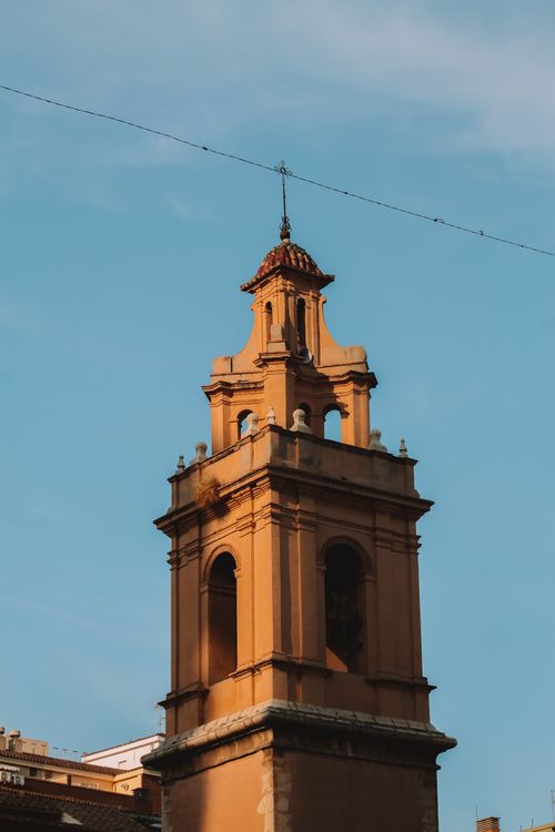 Free A historic clock tower rises against a clear blue sky in a sunny setting. Stock Photo