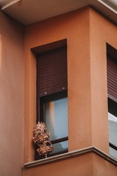 Close-up of building corner with palm decorations in a window, emphasizing architectural style.
