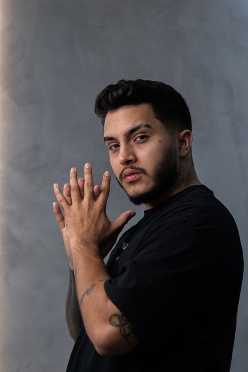 Free Portrait of a young man with tattoos posing seriously against a gray background. Stock Photo