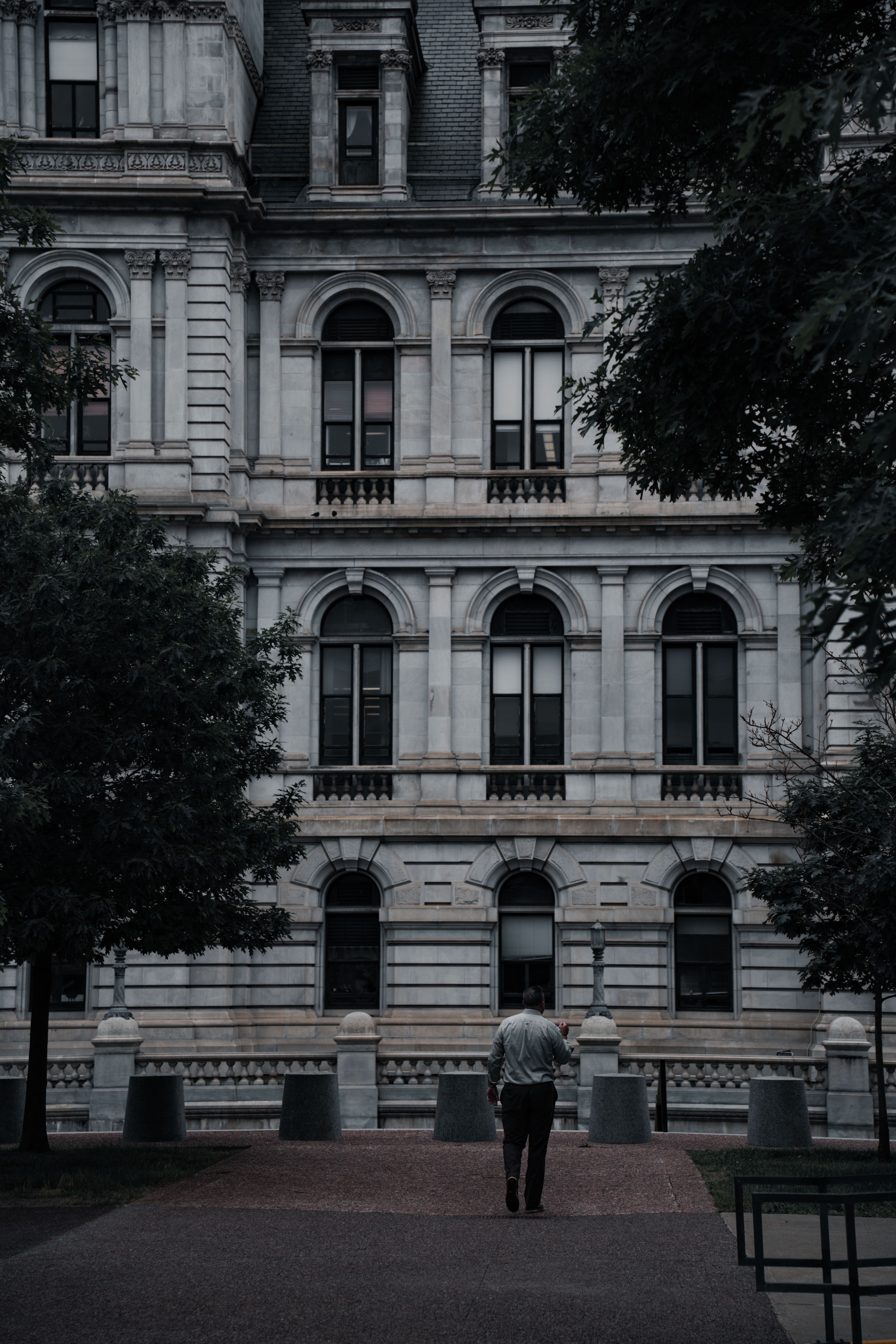 A man walking down a sidewalk in front of a large building · Free Stock ...